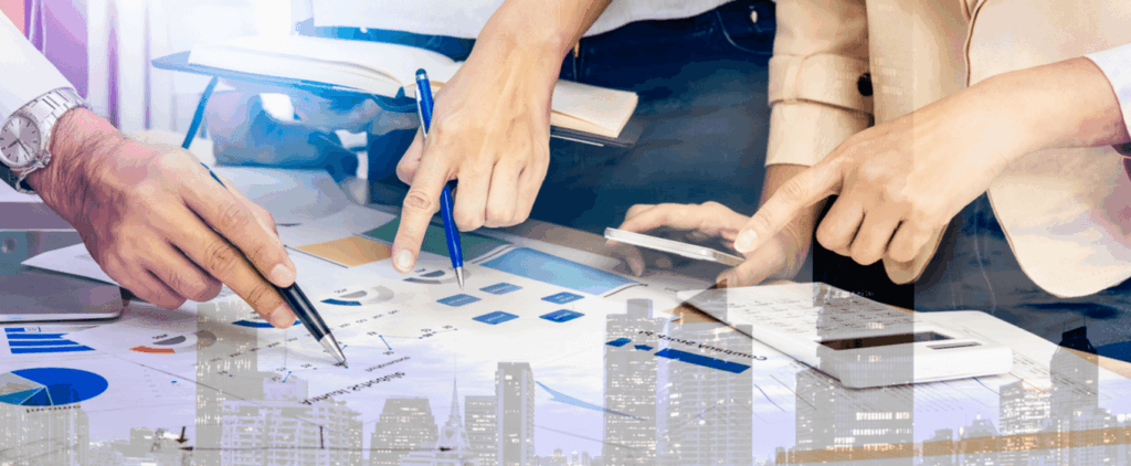Business professionals collaborate at a table with a city skyline visible in the background.