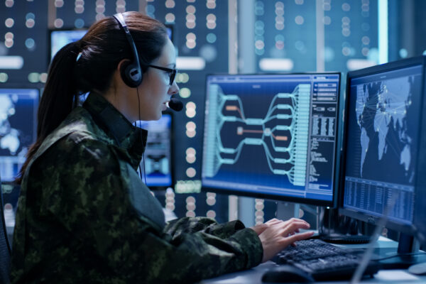 Shot of Female Government Agent Tracking Fugitive with Her Computer in Big Monitoring Room Full of Computers with Animated Screens
