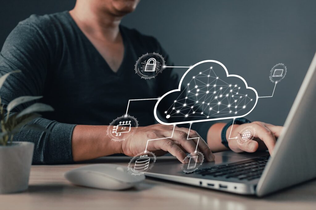 Execution and implementation A man types on a laptop with a holographic cloud network diagram showing icons for data, AI, security, and devices.