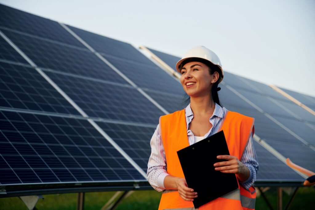 Female engineer conducting an onsite inspection of a solar farm in front of solar panels behind her