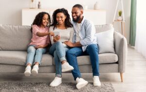 OneFamily - Family viewing financial products on a mobile phone sitting on a sofa