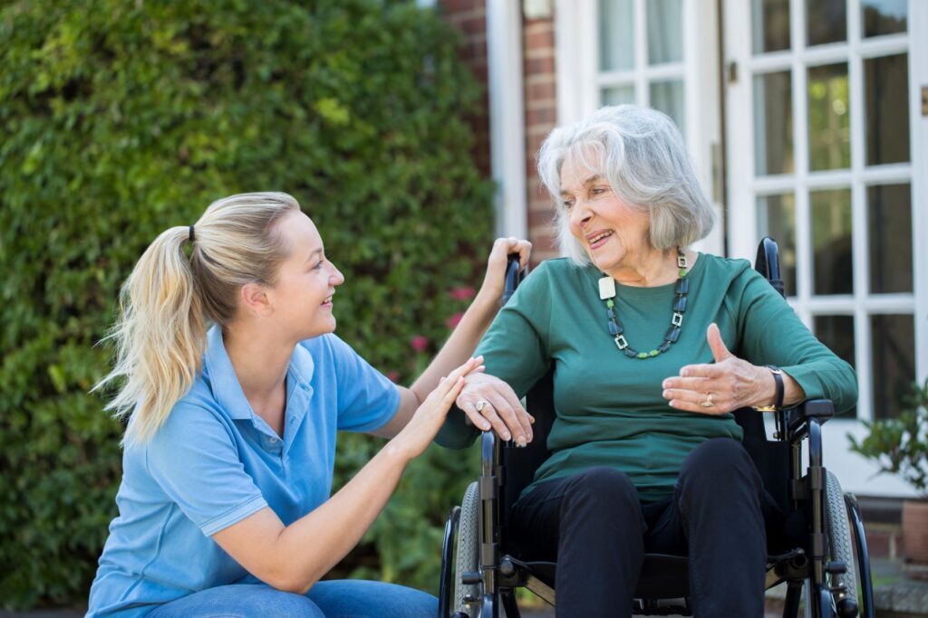Female carer caring for elderly woman in a wheelchair in outdoor space