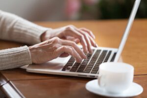 North Somerset Council - Woman typing on laptop with a mug of coffee on a desk