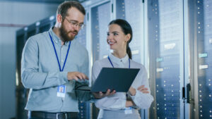 Centrica - IT Technicians talking with each other in a sever room while holding a laptop