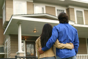 Knight Frank - Couple embracing each other standing in front of their new house
