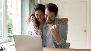 Allwyn - Couple celebrating in front of laptop after winning the lottery