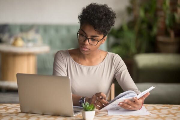Caerphilly County Borough Council - Woman studying using laptop and writing down notes