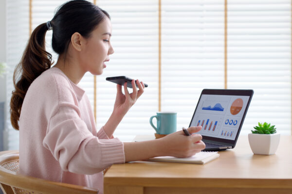 Woman talking on her phone while working on analytics on her laptop