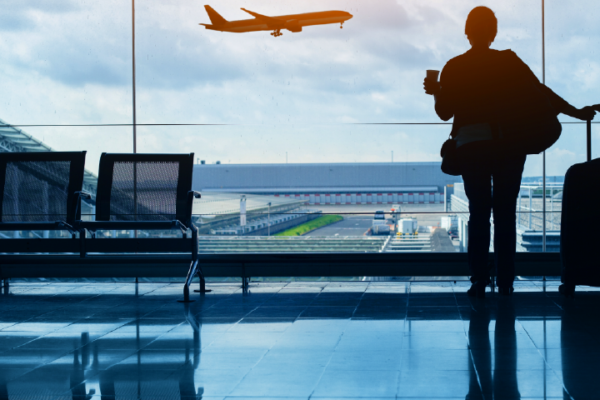 EasyJet - Female traveller looking at a plane departing in a airport departure room