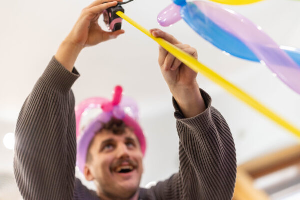 Jake blowing up balloons, smiling.