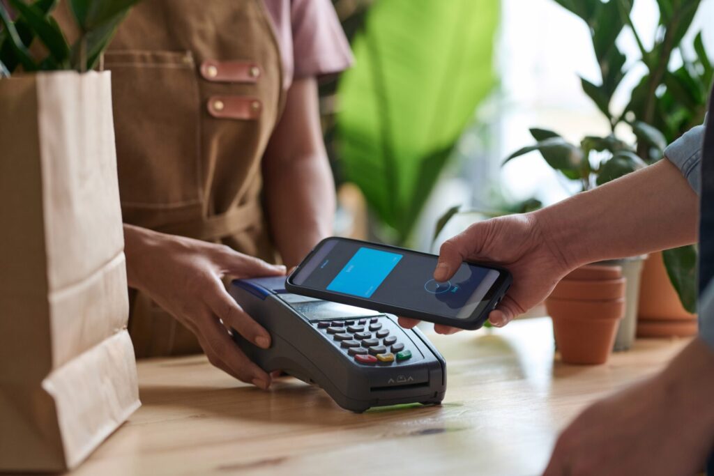 Customer using contactless way of payment with her smartphone at plant shot