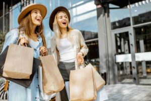 Portrait of a two happy women with shopping bags, standing together in front of the shopping mall
