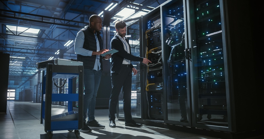 Managed Endpoint Response and Detection - Technicians inspect and maintain server racks in a modern data center, using a tablet to monitor equipment, check connections in a server space
