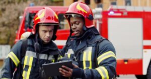 Essex Fire and Rescue firefighters in front of a red firetruck talking to each other